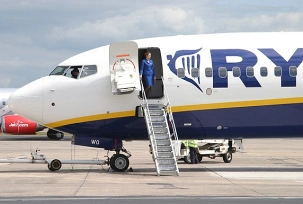 Eine Flugbegleiterin der Ryanair wartet auf Passagiere. Im Cockpit bereiten sich die Piloten vor., © AirTeamImages.com/Simon Willson