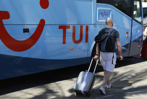Ein Passagier geht mit einem Koffer an einem Tui-Bus vorbei., © DPA/Clara Margais