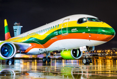 Ein Airbus A220 von Air Baltic mit Sonderbemalung der litauischen Flagge steht bei Nacht auf dem Vorfeld., © AirTeamImages.com/Yochai