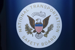 Das Siegel der Nationalen Verkehrssicherheitsbehörde, des National Transportation Safety Board, hängt bei einer Pressekonferenz am Ronald Reagan Washington National Airport, in Arlington., © DPA/Jose Luis Magana/AP