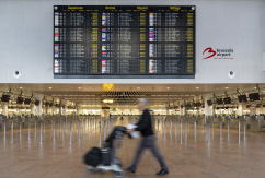 Infotafel zeigt die gestrichenen Flüge aufgrund eines Streiks am Brüsseler Flughafen an, während ein Reisender einen Gepäckwagen im Terminal schiebt., © DPA/Marius Burgelman