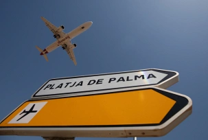 Ein Eurowings-Flugzeug fliegt über ein Schild mit der Aufschrift 'Platja de Palma', kurz vor der Landung am Flughafen Palma de Mallorca, © DPA/Clara Margais