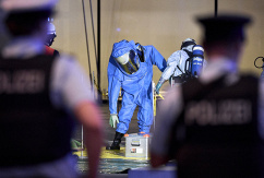 Ein Mitglied der Feuerwehr in einem Chemikalienschutzanzug wird von einem Kollegen vor dem Terminal 1 am Flughafen BER dekontaminiert., © DPA/Michael Ukas