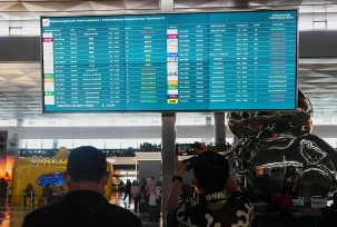 Reisende gehen am internationalen Flughafen Jakarta an einer Informationstafel vorbei, auf der Flugausfälle angezeigt werden., © DPA/Tatan Syuflana