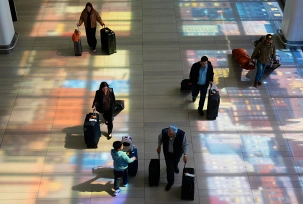 USA, New York: Buntglasfenster werfen farbige Schatten auf den Boden, als Reisende durch den LaGuardia Airport gehen, © DPA/Seth Wenig/AP