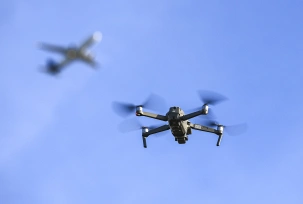 Eine Drohne fliegt vor einem startenden Flugzeug in der Nähe eines Flughafens., © DPA/Jan Woitas