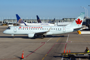 Eine Embraer ERJ-175 von Air Canada rollt über den Flughafen Chicago O'Hare während United-Flugzeuge im Hintergrund zu sehen sind., © AirTeamImages.com/Bruce Leibowitz